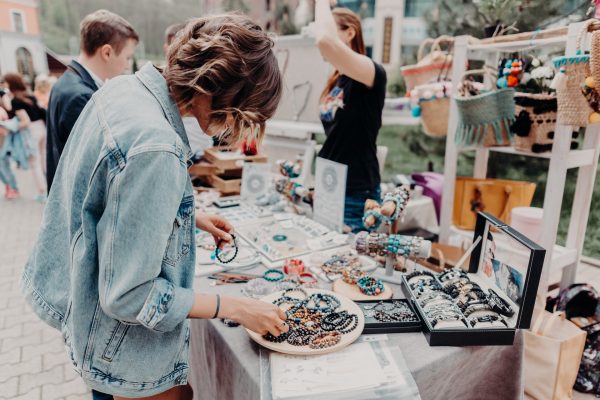 Woman looking through handmade bracelets at an outdoor craft fair or market